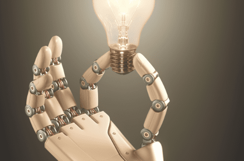 robot hand holding lit lightbulb representing demystifying tech terms